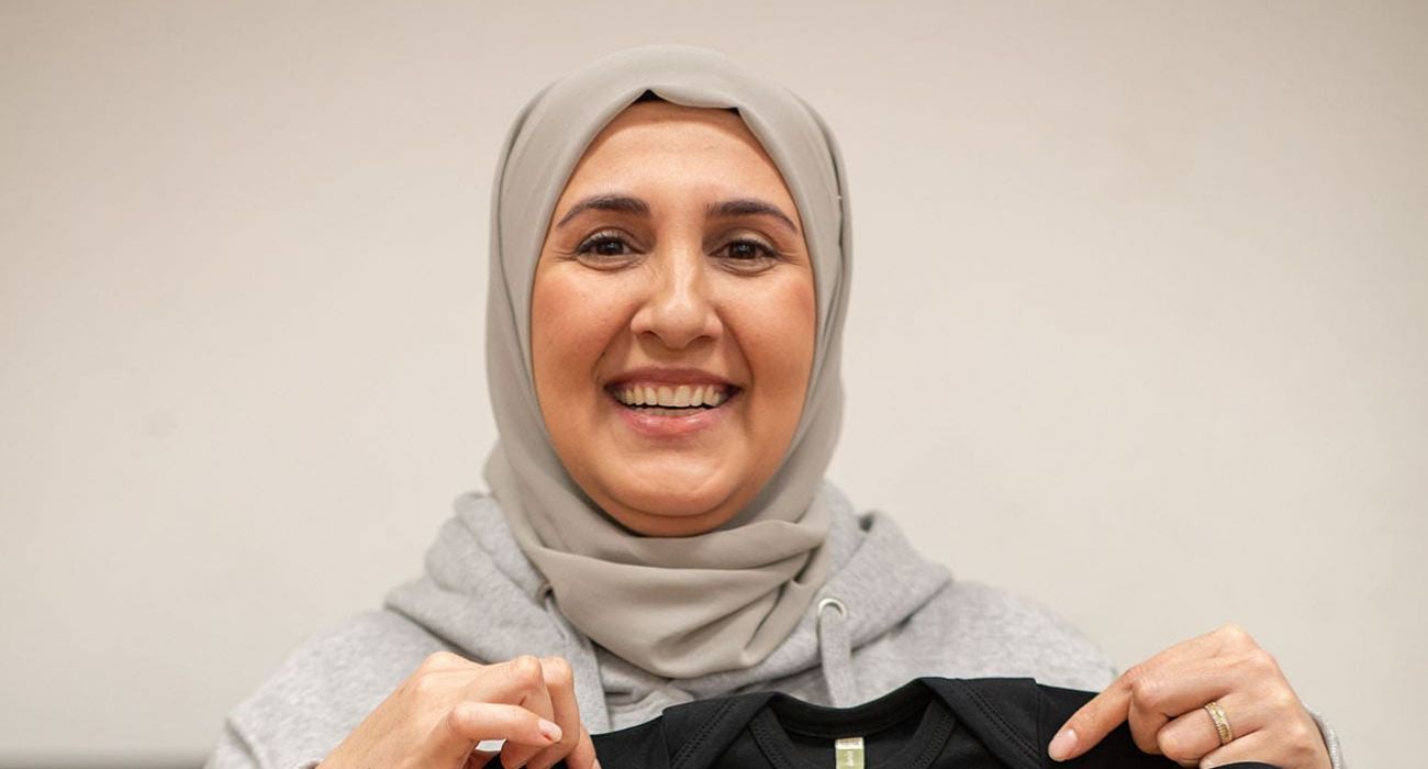 Jamile zeigt ihr Geschenk: ein MITmacher-Body für das Baby