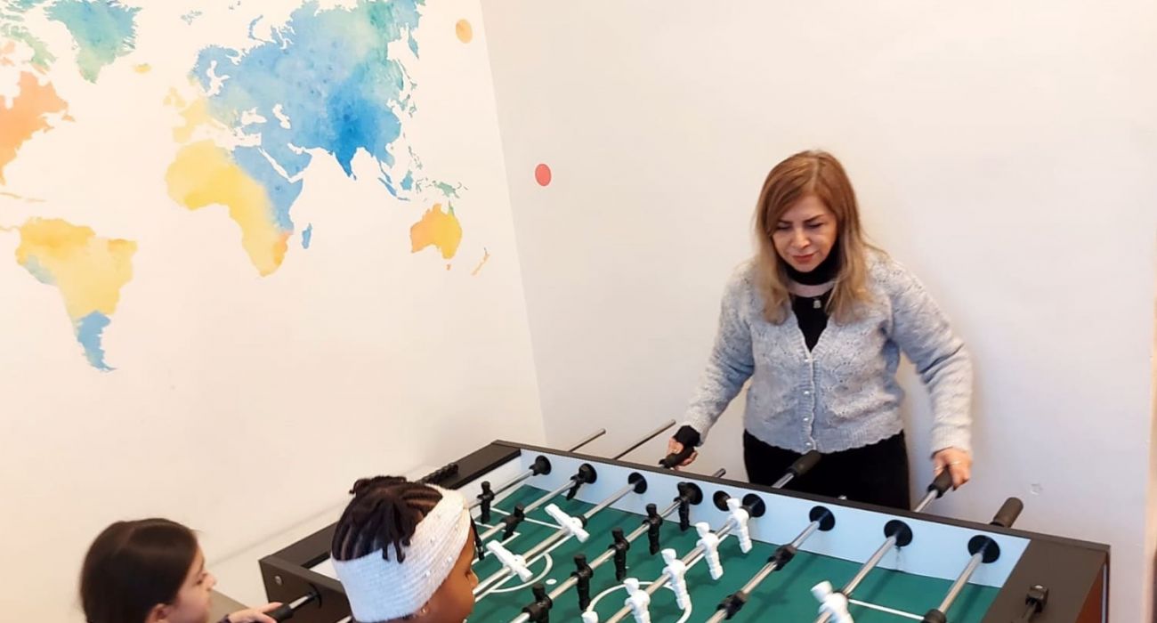 Masoumeh spielt mit zwei Mädchen Tischfußball