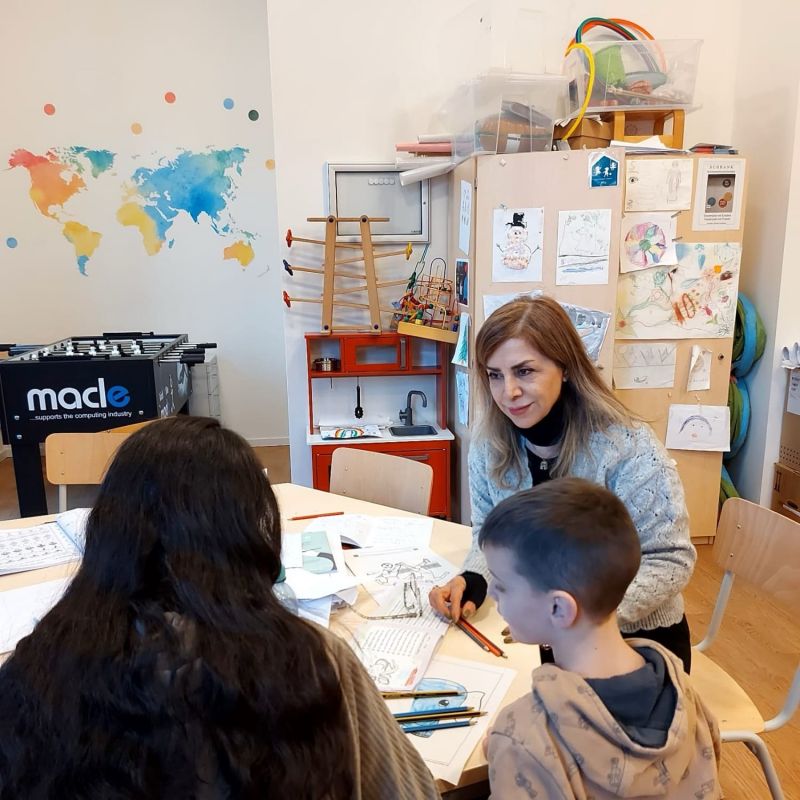 Masoumeh sitzt mit zwei Kindern an einem Tisch.