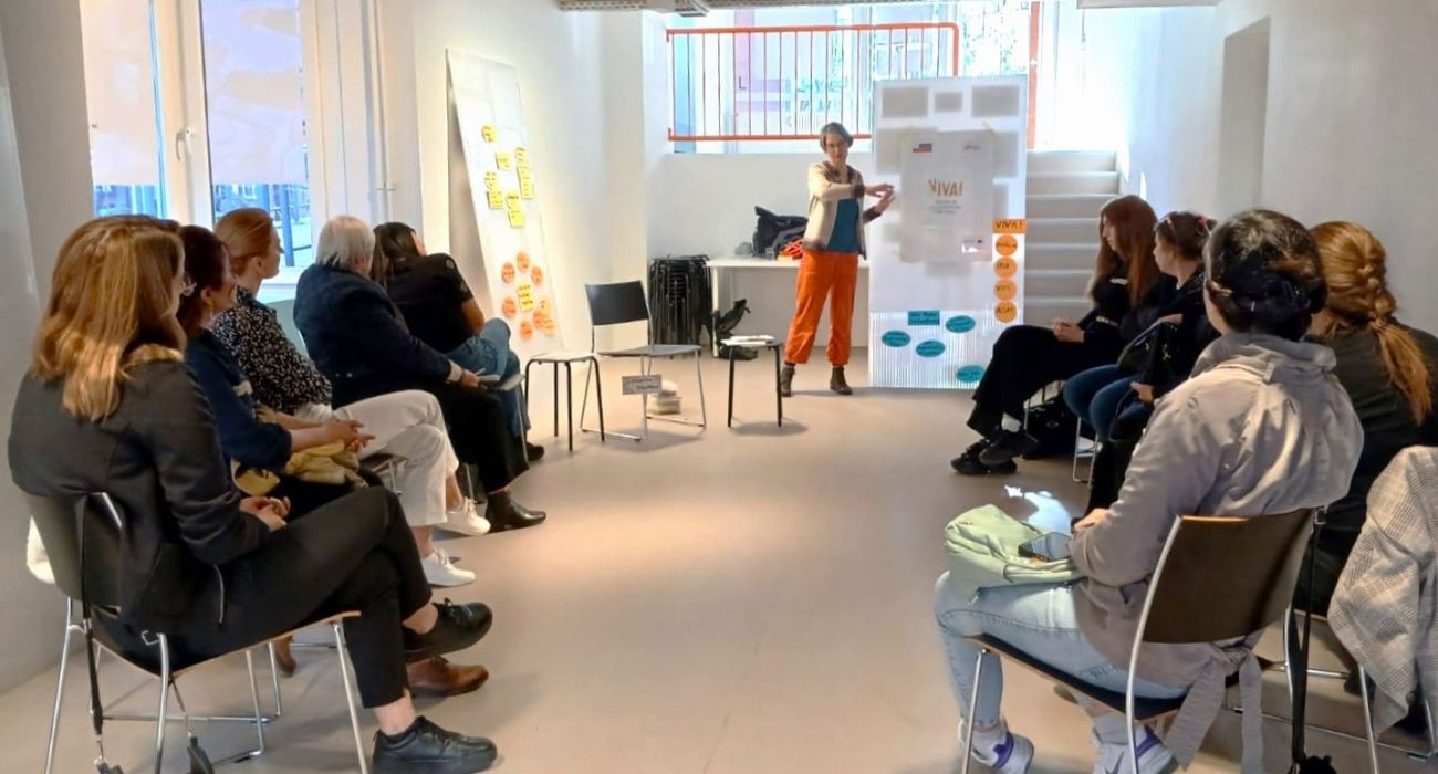 Die Teilnehmenden sitzen im Kreis und schauen die Referentin der VHS Hamburg an.