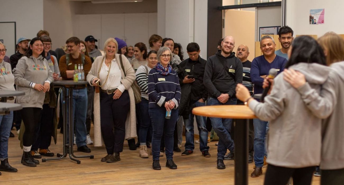 Ehrenamtliche und Menschen aus sozialen Organsationen stehen zusammen und lachen.