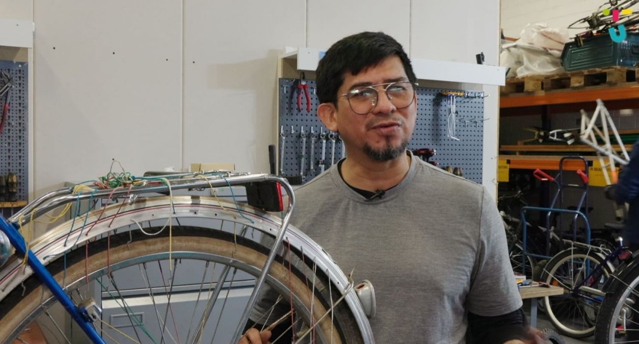 Juan steht neben einem Fahrrad und spricht.