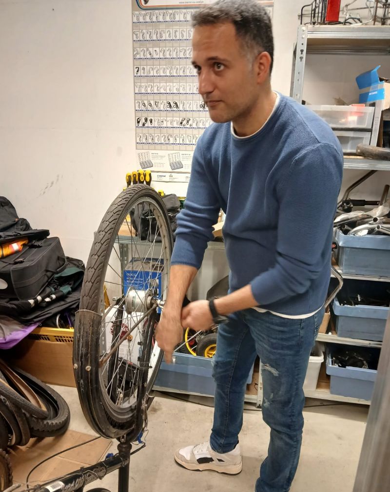 Rafat steht neben einem Fahrrad, das er gerade repariert.